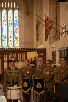 The Lone Drummer and military band underneath the Cathedral's Gallipoli flag