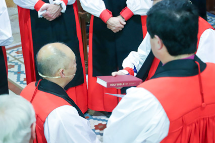 The Archbishop hands Bishop Koo the Bible.